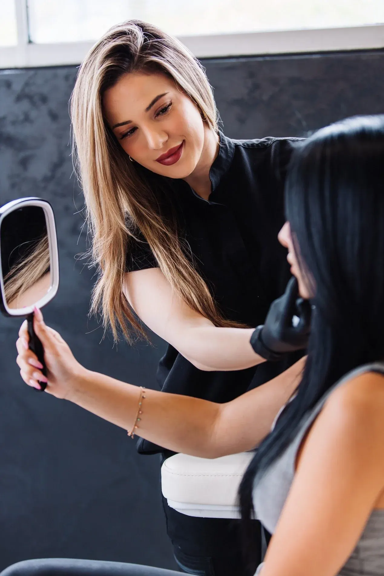 Katherine showing a patient her skin in a hand mirror after a treatment