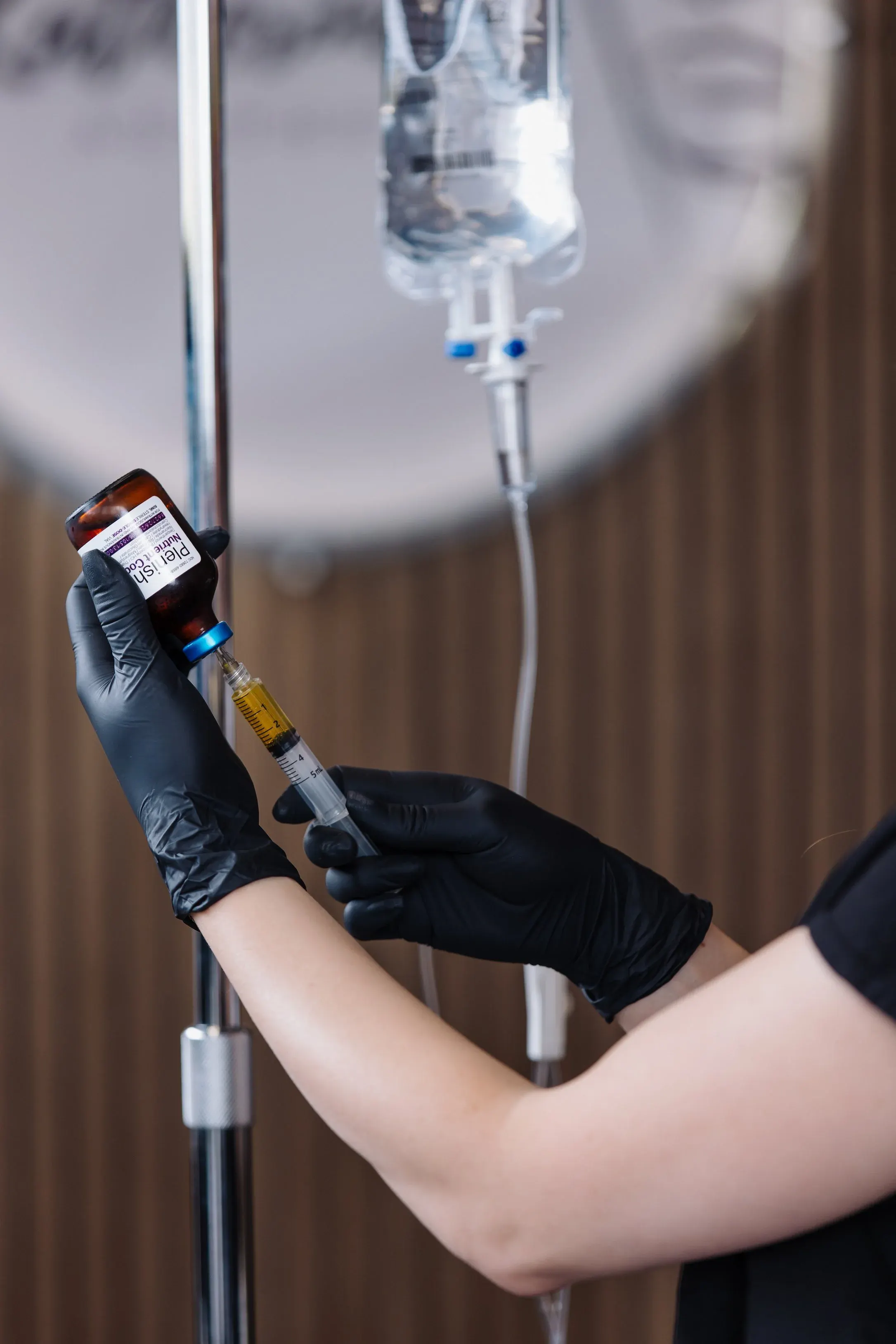 Drawing a nutrient blend into a syringe beside a hanging IV bag